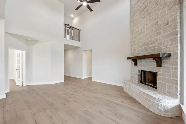 a view of an empty room with wooden floor fireplace and a window