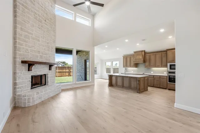 a large kitchen with a stove a sink dishwasher a kitchen island with wooden cabinets and floor