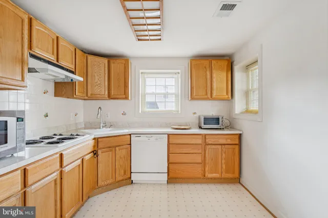 a kitchen with cabinets appliances a sink and a window