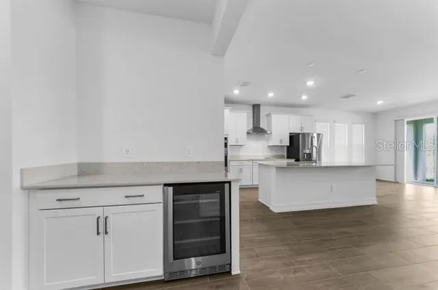 a view of kitchen with stainless steel appliances granite countertop a stove a sink a refrigerator and white cabinets with wooden floor