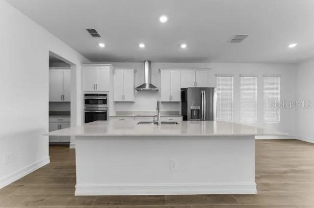a large kitchen with stainless steel appliances a large counter top and a stove top oven