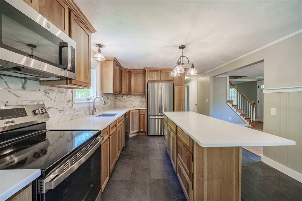 313 Bennett Road Hampden, MA 01036 - Photo 16 of 42 a kitchen with kitchen island granite countertop a stove top oven a sink dishwasher and wooden cabinets