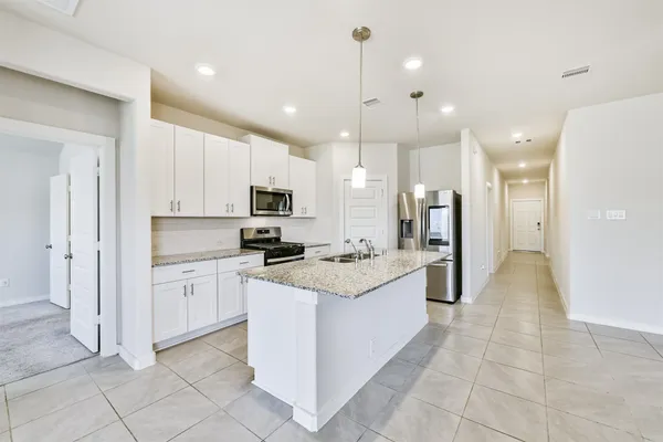 a large kitchen with stainless steel appliances kitchen island granite countertop a stove a sink and a refrigerator
