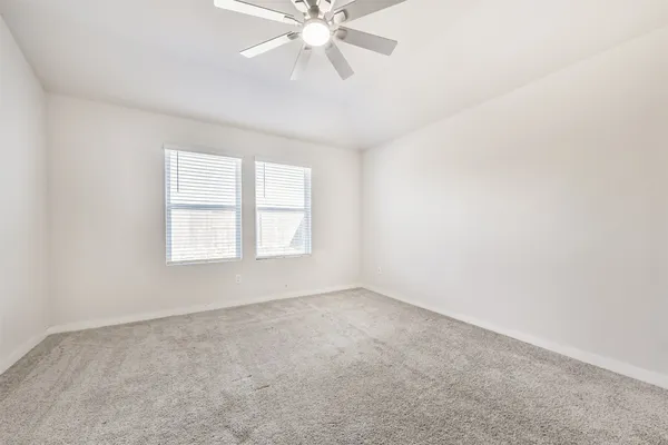 an empty room with a window and a fan