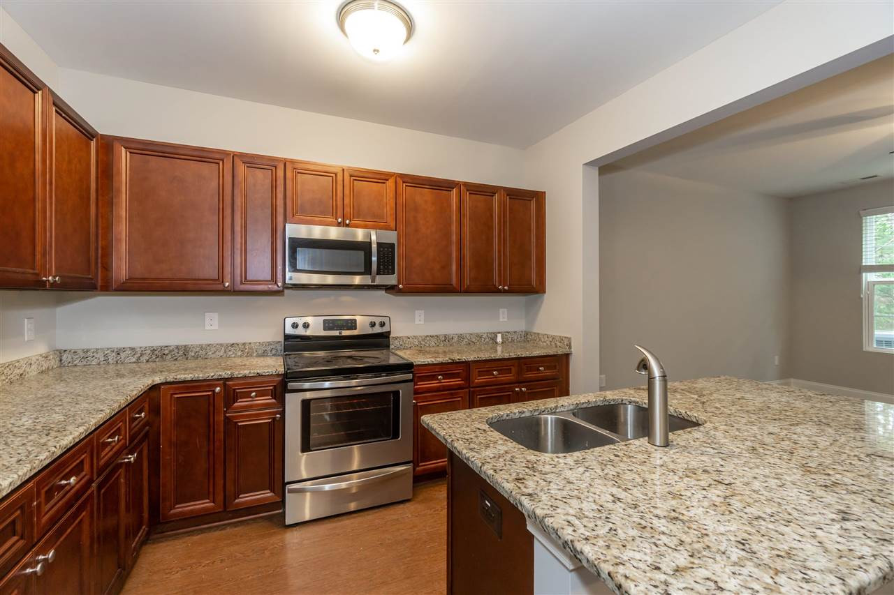 3934 Volkswalk Place Raleigh, NC 27610 - Photo 5 of 16 a kitchen with granite countertop a stove top oven microwave and cabinets