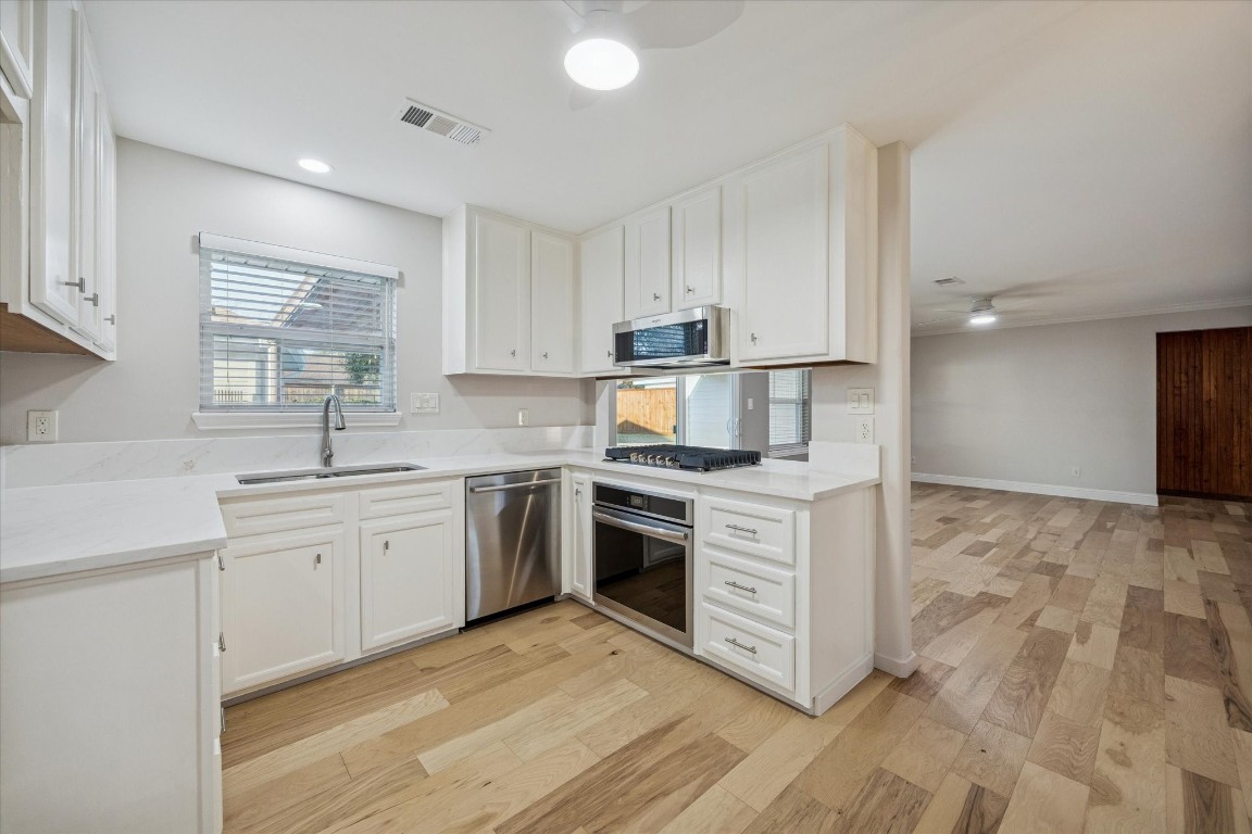 10422 Raritan Drive Houston, TX 77043 - Photo 8 of 31 a kitchen with granite countertop white cabinets a sink dishwasher and a stove with wooden floor