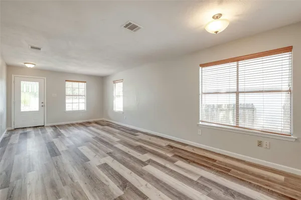 a view of an empty room with wooden floor and a window