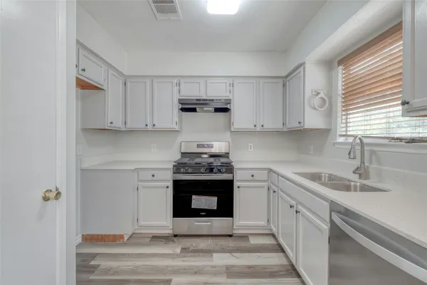 a kitchen with stainless steel appliances granite countertop a stove and white cabinets