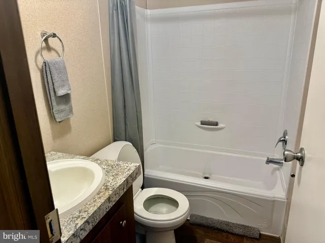 a bathroom with a granite countertop toilet sink and mirror