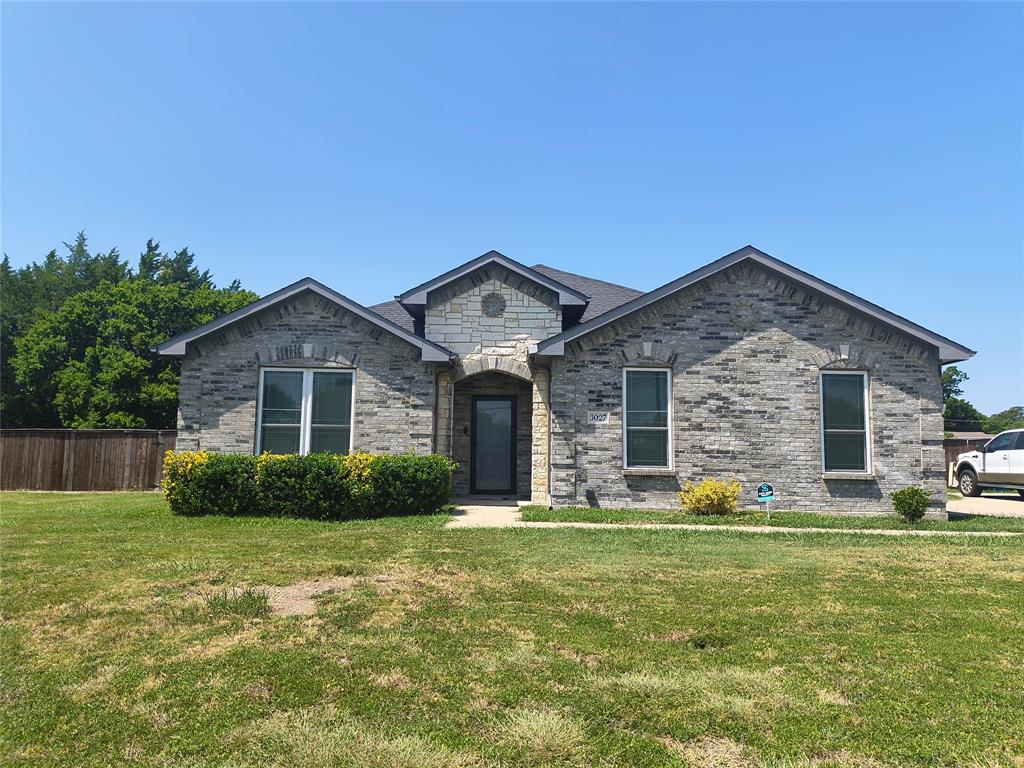 Single-story residence featuring a gray brick exterior with light stone accents, dark-framed windows, and a dark shingle roof
