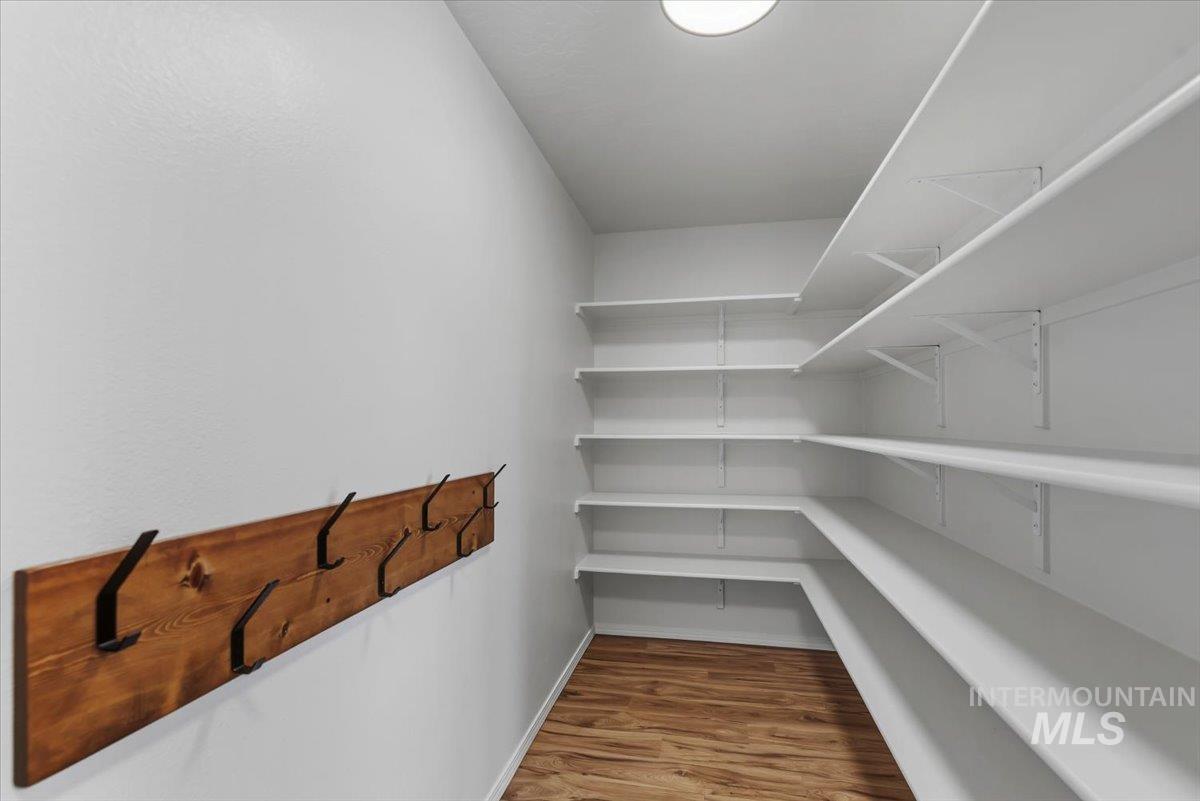 12310 West Hidden Point Drive Star, ID 83669 - Photo 12 of 48 Spacious pantry featuring extensive white shelving, wood-finish flooring, and a ceiling-mounted light fixture