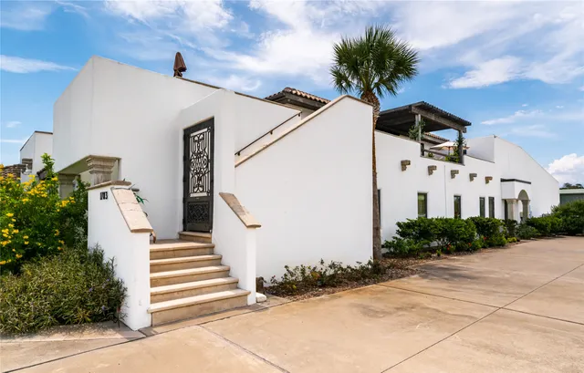 a view of a white house with a potted plant ana a small yard