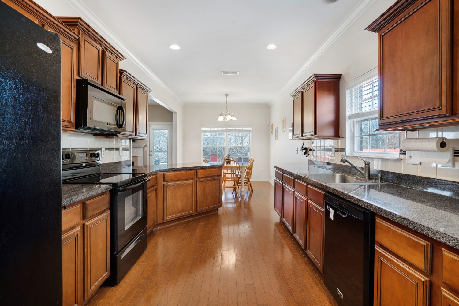 4078 Locerbie Circle Spring Hill, TN 37174 - Photo 8 of 40 a large kitchen with stainless steel appliances granite countertop a stove a sink dishwasher and a microwave oven with wooden cabinets