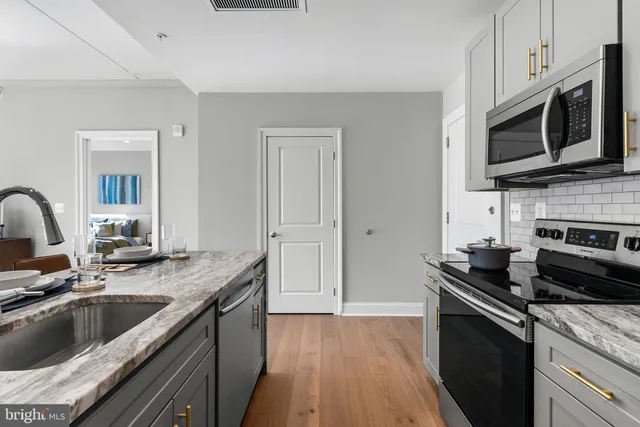 a kitchen with granite countertop a sink dishwasher stove and microwave with wooden floor