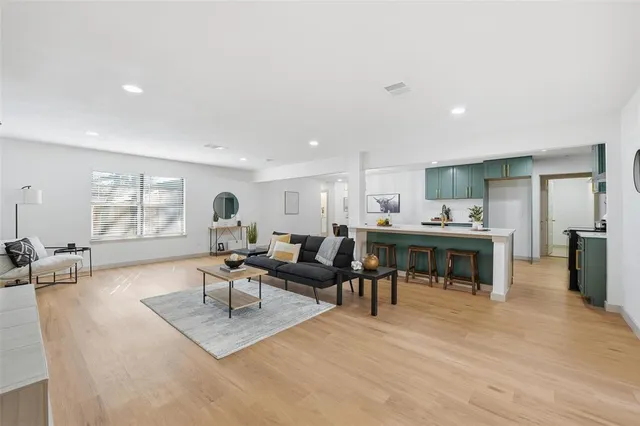 a living room with furniture a wooden floor and kitchen view