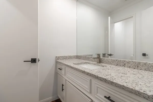 a bathroom with a granite countertop sink and white cabinets
