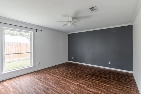 an empty room with wooden floor ceiling fan and windows