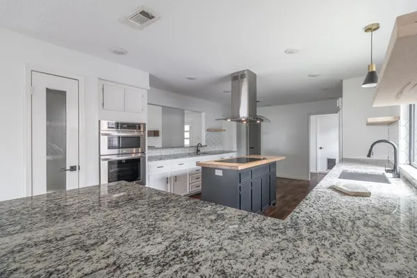 a large kitchen with kitchen island granite countertop a sink stove refrigerator and cabinets