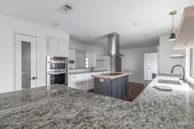 a large kitchen with kitchen island granite countertop a sink stove refrigerator and cabinets