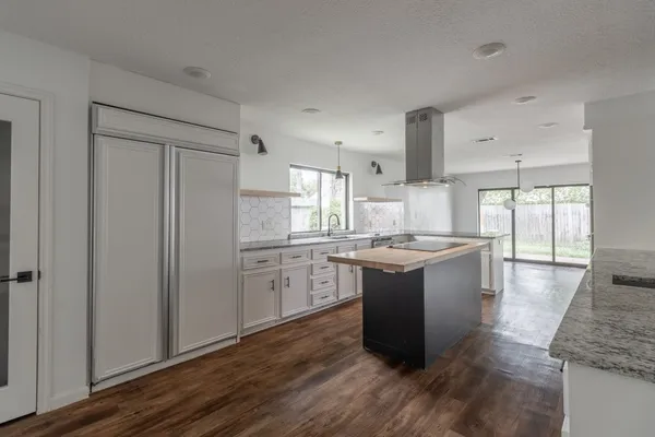 a large kitchen with a large counter top a sink stainless steel appliances and cabinets