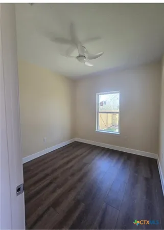 an empty room with wooden floor ceiling fan and window