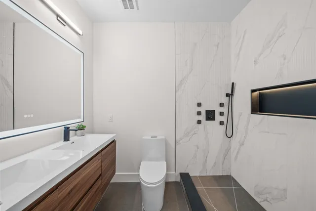 a bathroom with a granite countertop sink toilet and shower