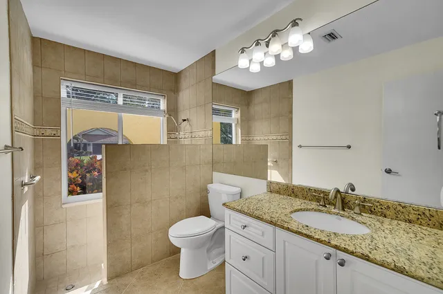 a view of an empty room with wooden floor and a ceiling fan