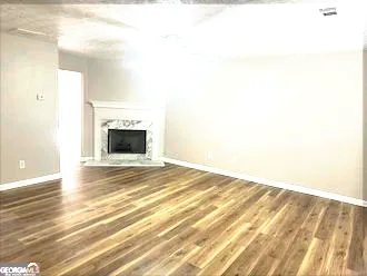 a view of an empty room with wooden floor and a fireplace