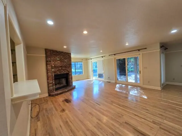 a view of empty room with wooden floor and fireplace