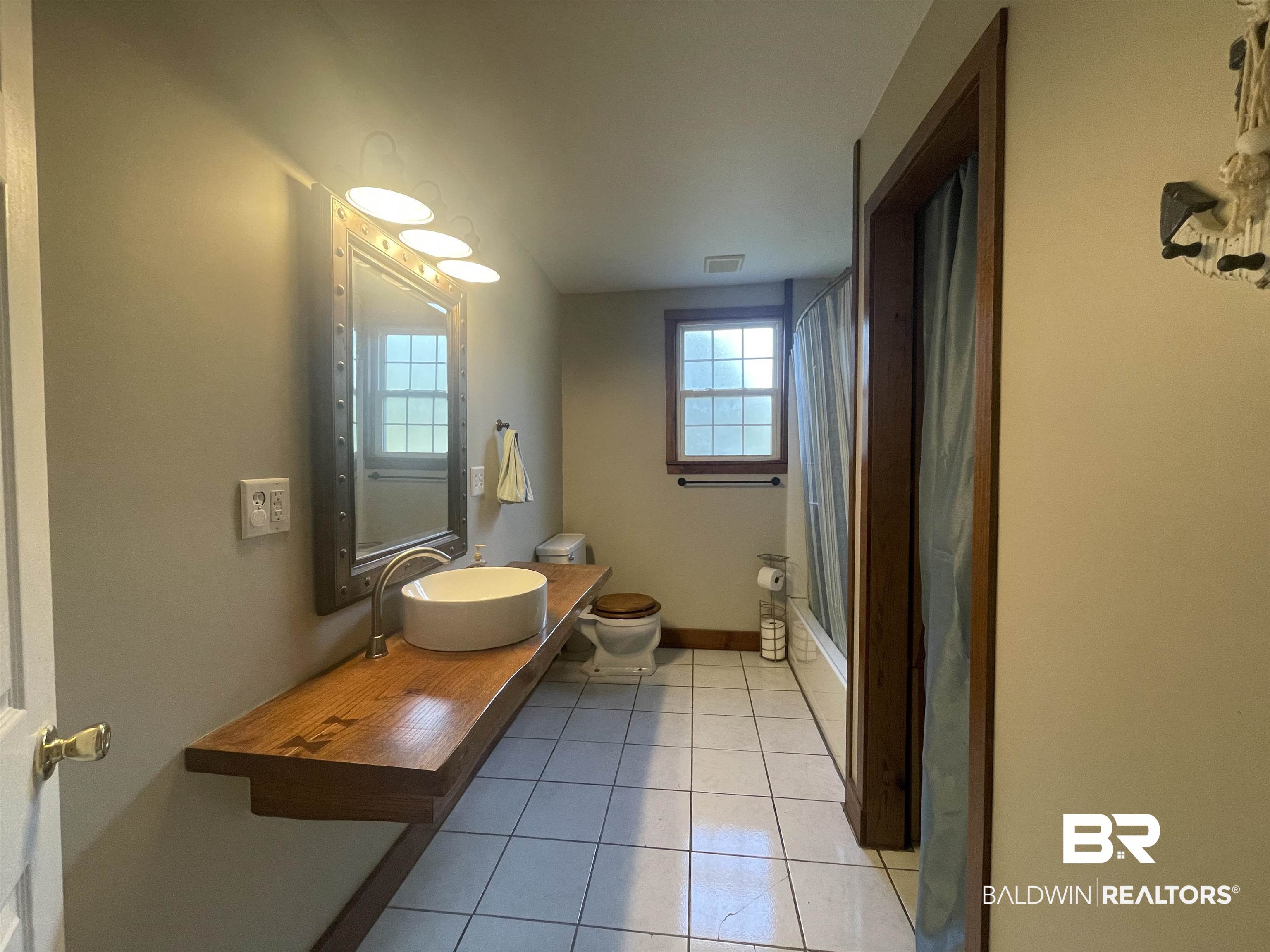 13850 Celeste Road Chunchula, AL 36521 - Photo 16 of 29 Bathroom with vanity, light tile patterned floors, and shower / bath combination with curtain