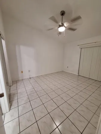 an empty room with windows and fan