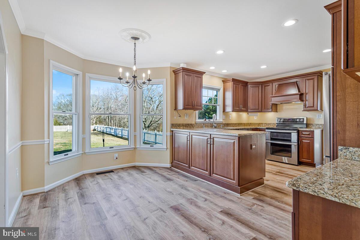 12630 Grosstown Road Hughesville, MD 20637 - Photo 12 of 44 a kitchen with stainless steel appliances granite countertop a stove top oven a sink and a chandelier