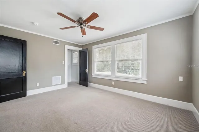 a view of a livingroom with a ceiling fan & windows