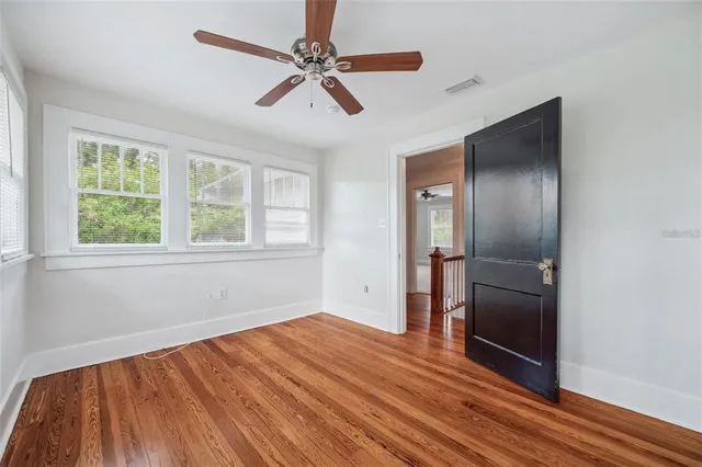a view of empty room with wooden floor and fan