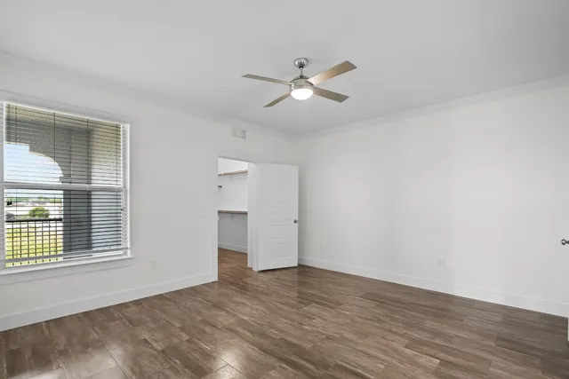a view of empty room with wooden floor and fan