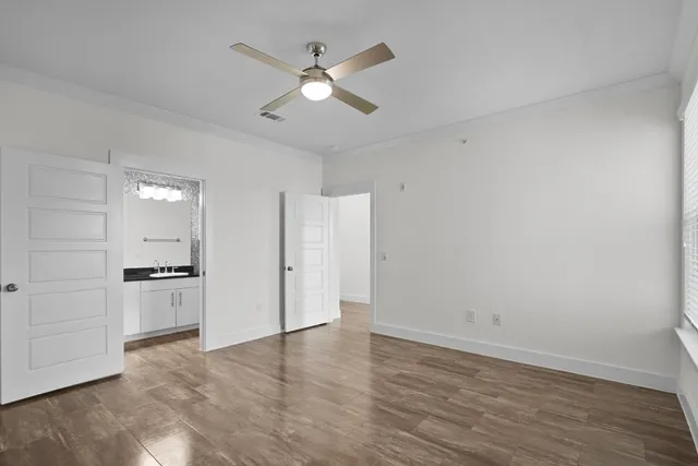 an empty room with wooden floor ceiling fan and windows