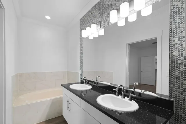 a bathroom with a sink a mirror and a bathtub with a chandelier