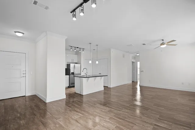 a view of kitchen and empty room with wooden floor