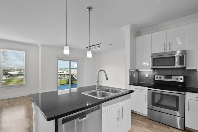 a kitchen with stainless steel appliances granite countertop a sink a stove and a refrigerator