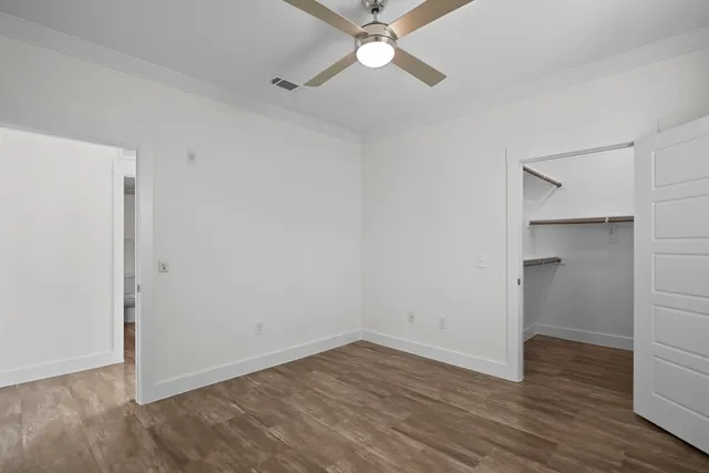 an empty room with wooden floor and ceiling fan