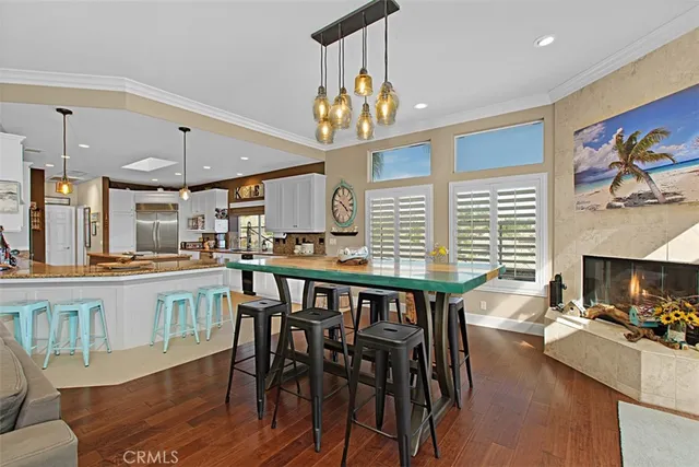 a kitchen with stainless steel appliances granite countertop a stove a refrigerator a kitchen island a dining table and chairs with wooden floor