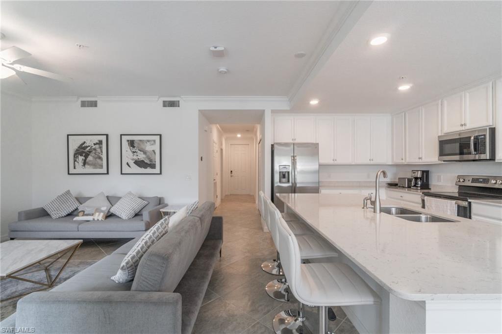 9596 Trevi Court, Unit 5426 Naples, FL 34113 - Photo 5 of 21 a large kitchen with kitchen island a large counter top space a sink stainless steel appliances and cabinets
