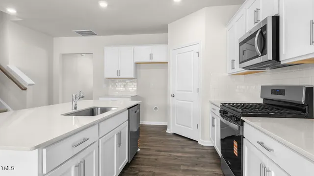 a kitchen with stainless steel appliances granite countertop a sink stove cabinets and wooden floor
