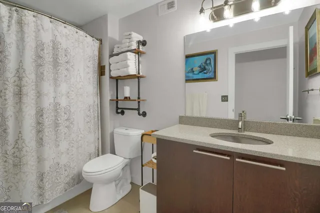 a bathroom with a granite countertop sink toilet and mirror