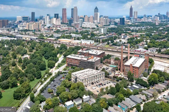 a view of a house with brick walls plants and large tree