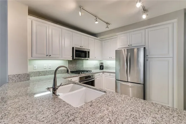 a kitchen with stainless steel appliances granite countertop a stove top oven a sink dishwasher a refrigerator and a oven with wooden floor