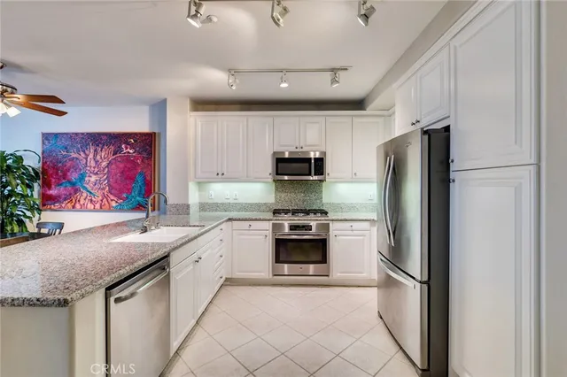 a kitchen with stainless steel appliances kitchen island granite countertop a table chairs cabinets and wooden floor