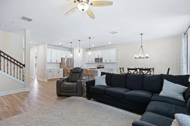 a living room with furniture kitchen view and a chandelier