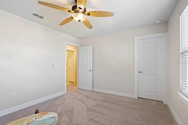 an empty room with closet and a chandelier fan