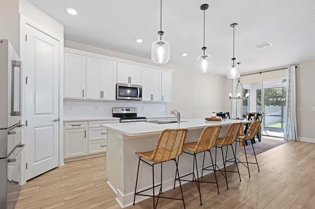 a kitchen with stainless steel appliances granite countertop a white cabinets and wooden floors
